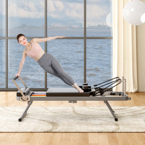Woman exercising on a Pilates reformer machine in a room with large windows showing a scenic view- TNT Fitness Gear